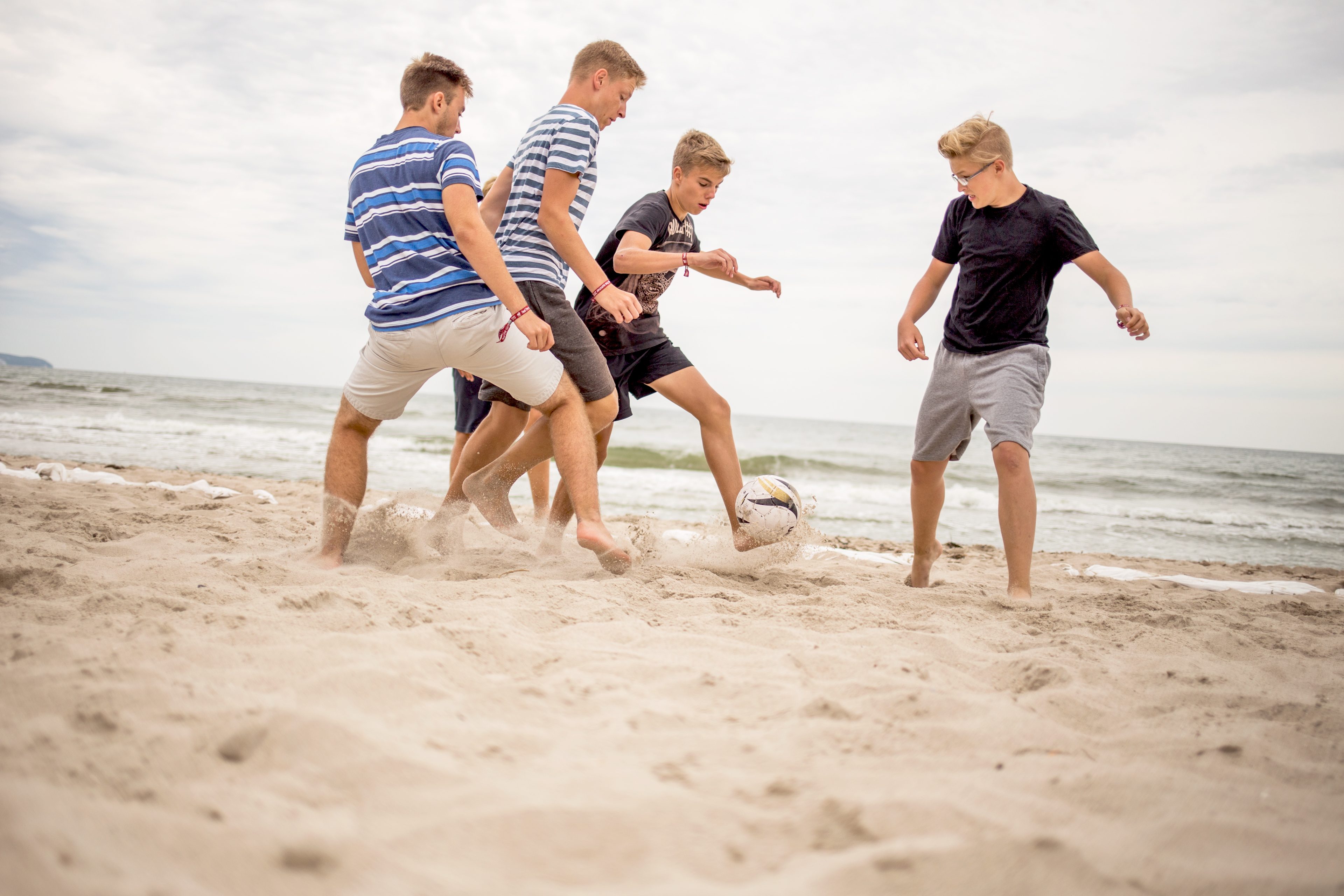 Gäste spielen Fussball am Strand