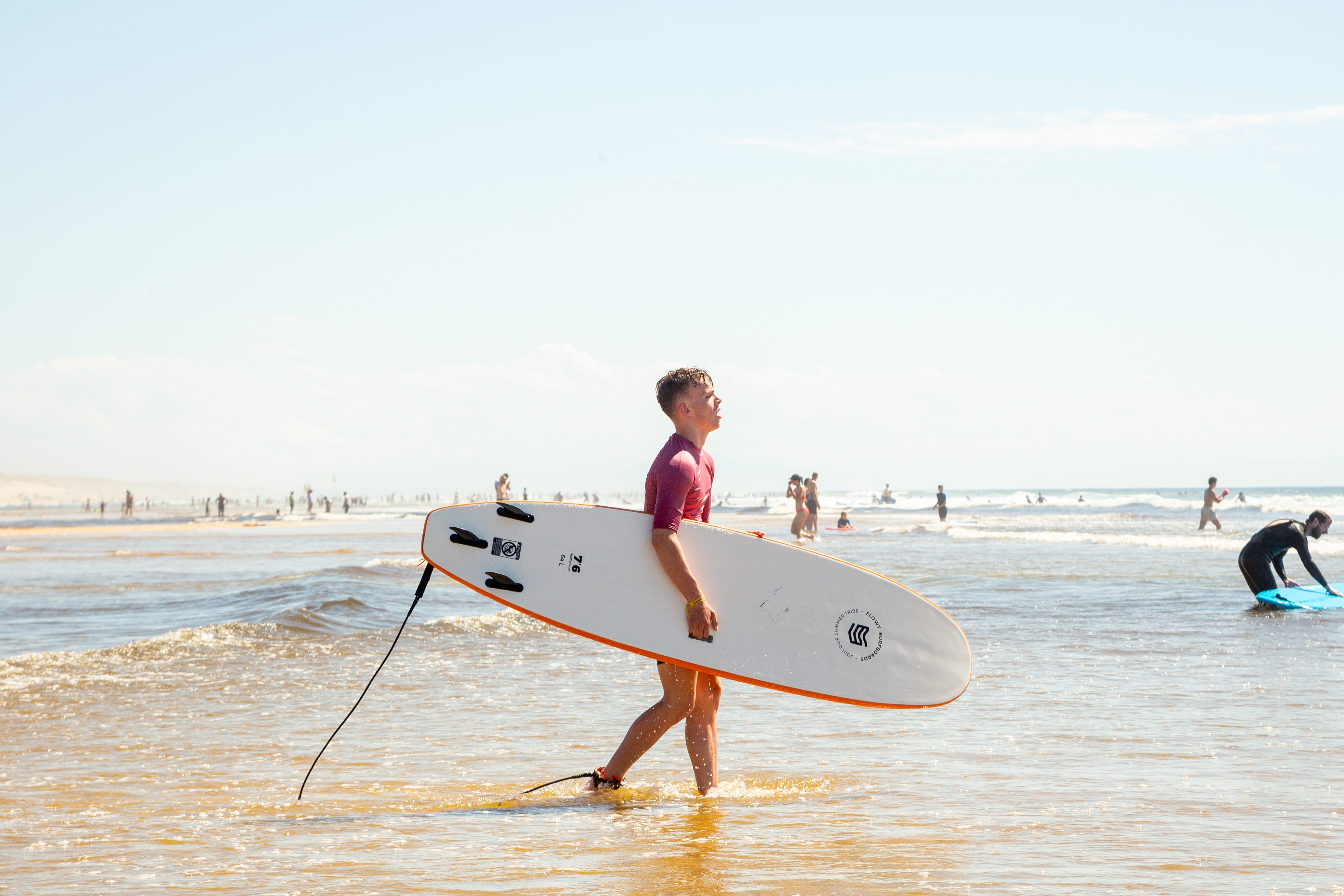 Reisegast mit Surfbrett am Strand