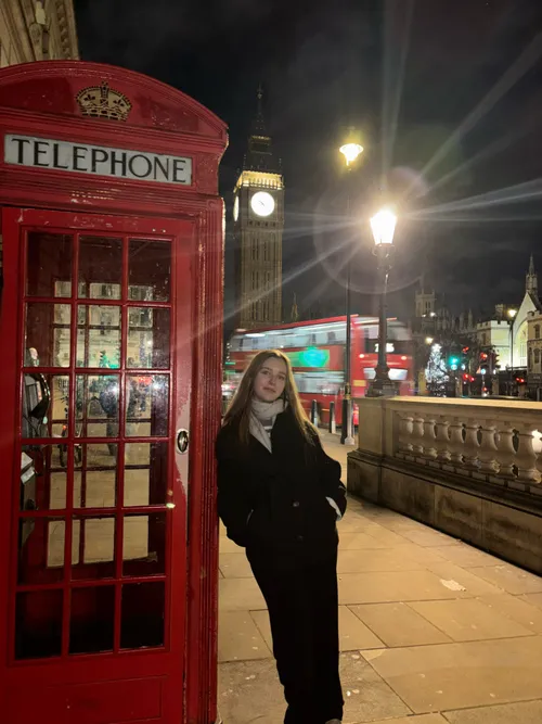 Mädchen lehnt an roter Telefonzelle