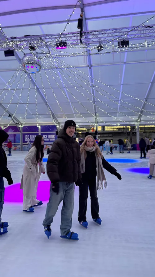 Gäste fahren Schlittschuh auf einer beleuchteten Eisabahn