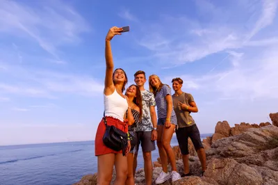 Reisegäste mit Handy am Meer