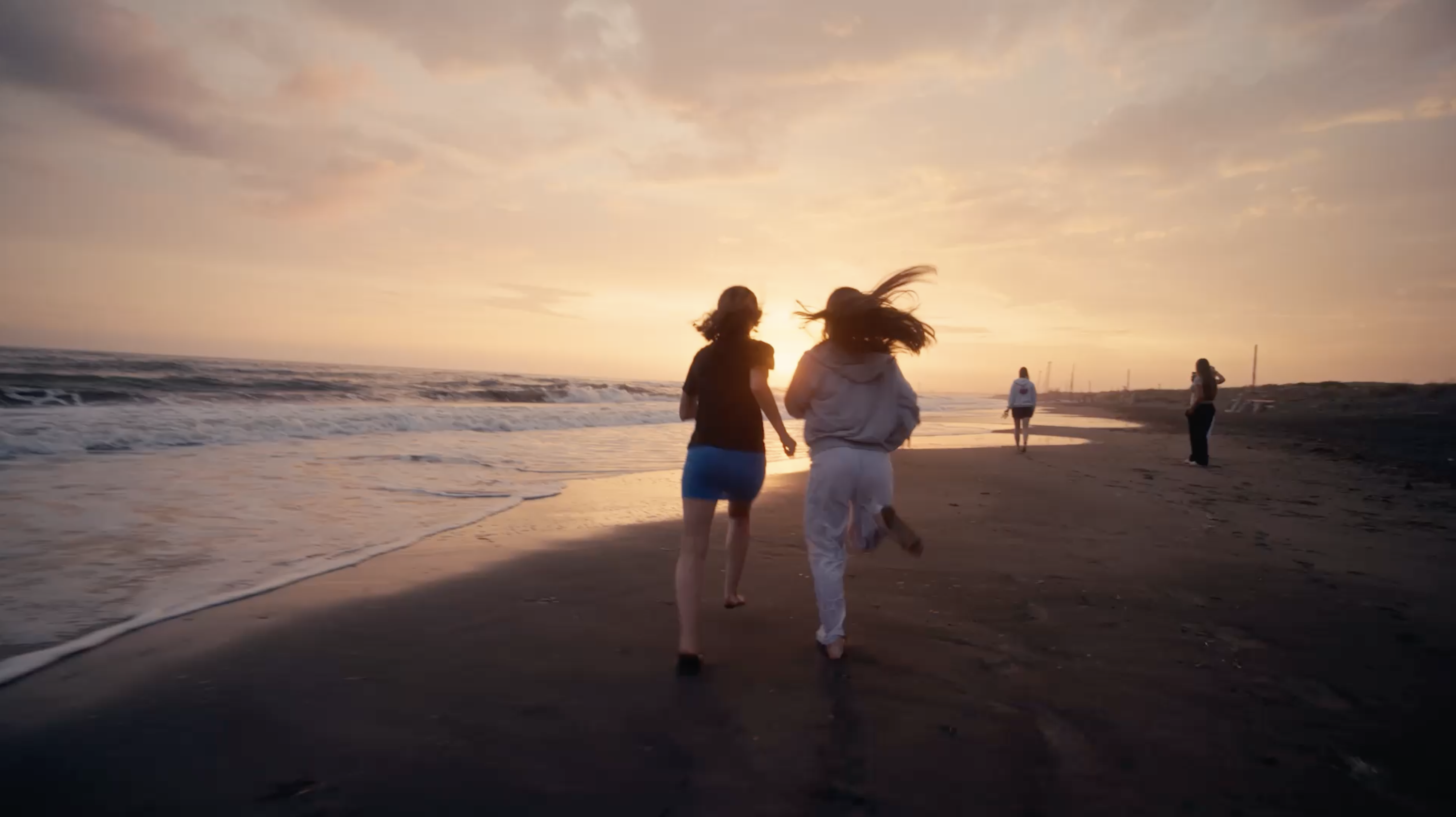 Zwei Freundinnen laufen in den Sonnenuntergang am Strand