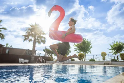 Reisegast mit Flamingo springt in Pool