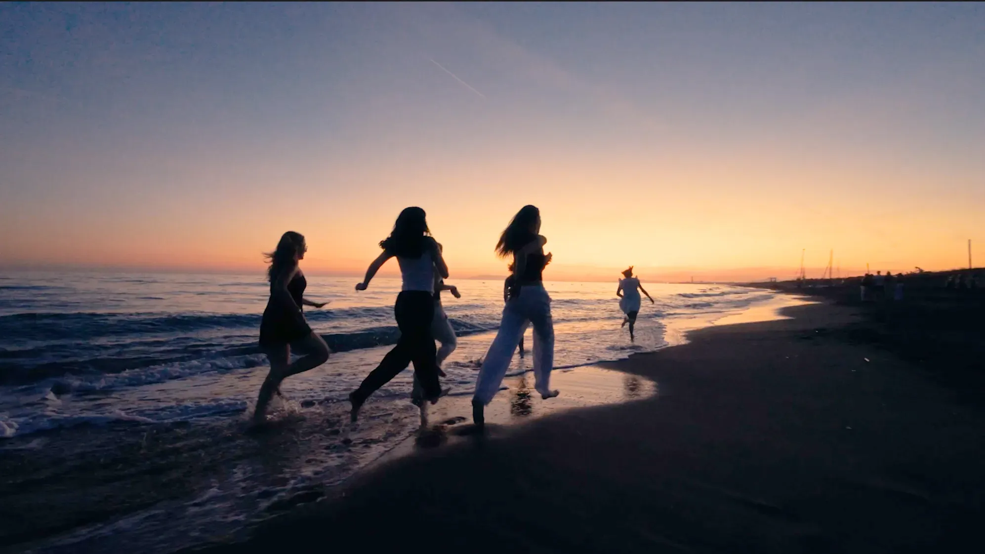 Jugendliche laufen bei Sonnenuntergang den Strand entlang