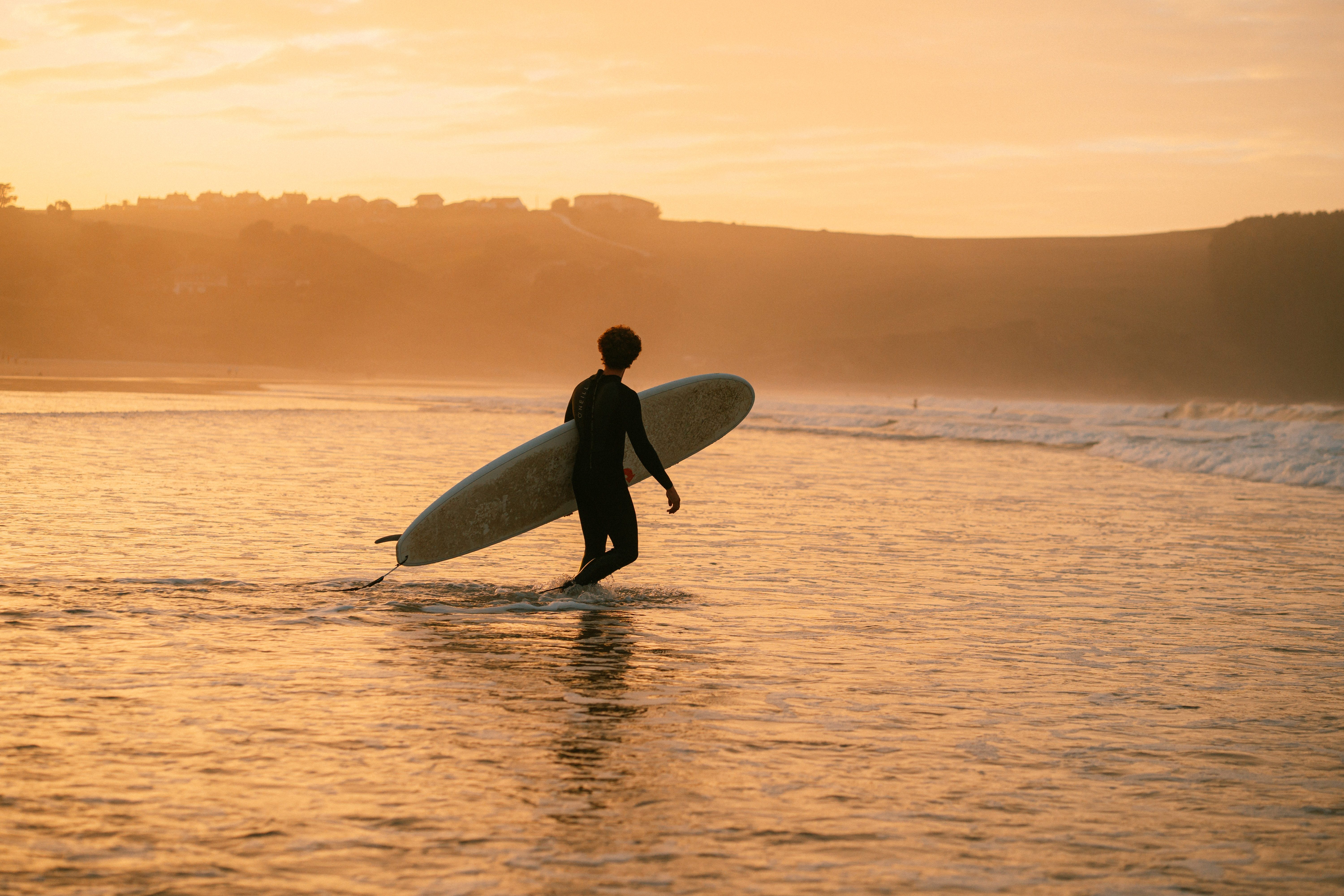 Person steht mit Surfboard im Wasser